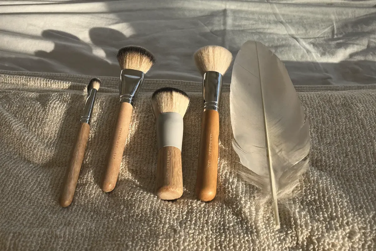 Soft brushes and a white feather laid out on a folded towel