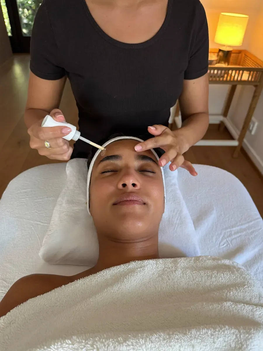 Serum being smoothed across a client's forehead during a facial